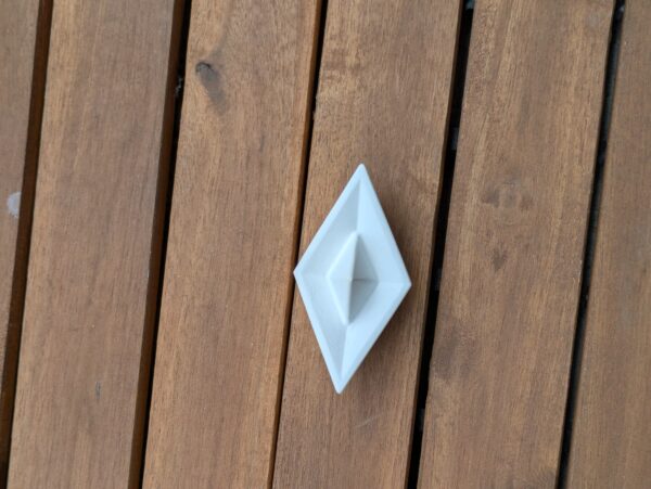 ein schiffchen aus gips von oben fotograafiert auf holzuntergrund